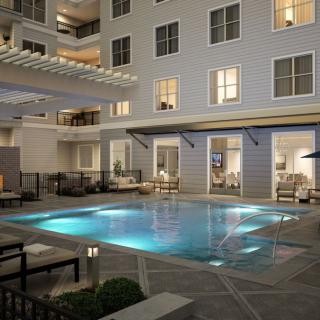 A beautifully lit swimming pool in a luxury hotel courtyard at night.