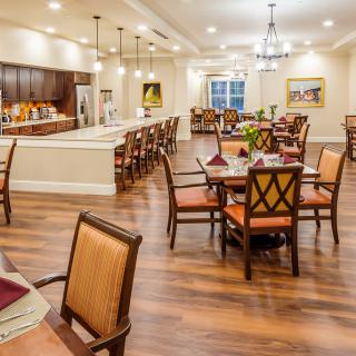 A beautifully designed dining area with neatly arranged tables and chairs, warm lighting, and a modern interior.