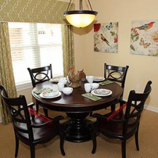 A cozy dining room setting with a round wooden table and four chairs, complete with elegant place settings and ambient lighting.