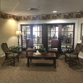 A cozy waiting area with comfortable chairs and a wooden table in a lobby setting.