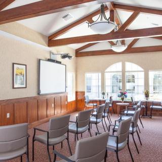 A well-lit meeting room with a projector screen and arranged chairs.