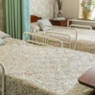 A hospital room with two beds arranged side by side, featuring floral-patterned bed covers.