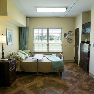 A well-decorated hospital room with a bed, window, and various furnishings.