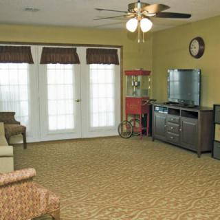 A cozy living room with a television and popcorn machine, featuring carpet flooring and large windows.