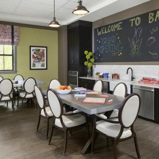 A modern dining area with a welcoming atmosphere, featuring a table, chairs, and a kitchenette.