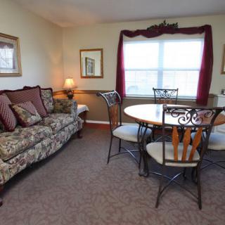 A cozy living room with a dining area featuring a patterned sofa, round dining table with chairs, and elegant decor.