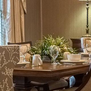 An elegantly set dining room table with a centerpiece of greenery.