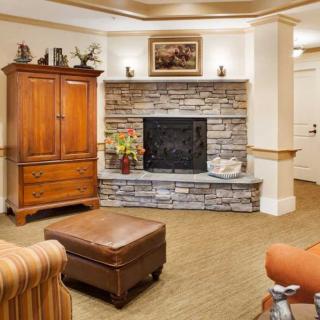 A cozy living room with a stone fireplace and wooden furniture.