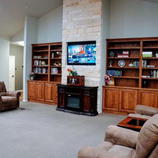 A cozy living room featuring built-in bookshelves, a central fireplace, and comfortable seating.