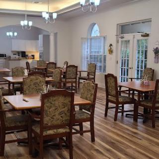 A spacious dining area with multiple tables and chairs, featuring wooden floors and elegant lighting.