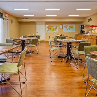 An empty dining area with neatly arranged tables and chairs, featuring maps on the wall.