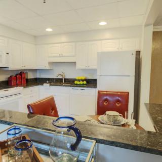 A modern kitchen with white cabinets and a dining area.