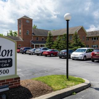 A view of a residential facility with a sign indicating its name and services, set against a cloudy sky.