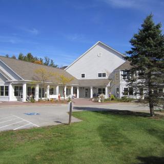 A large residential-style building with a well-maintained lawn and clear blue sky.