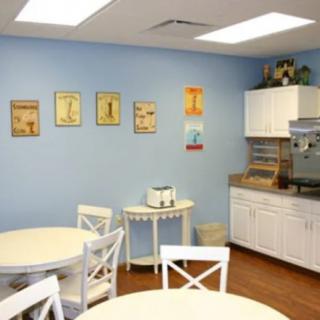 A cozy kitchen dining area with round tables, white chairs, and decorative wall art.