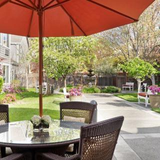 A peaceful patio area with a table, chairs, and an umbrella overlooking a garden.