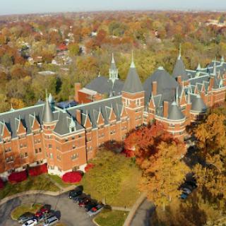 Aerial view of a historic university building surrounded by autumn foliage.