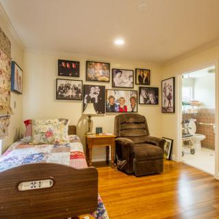 A cozy bedroom with a bed, recliner chair, and photographs adorning the walls.