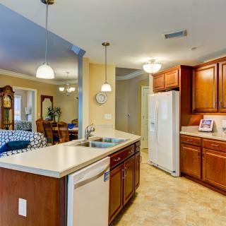 A modern kitchen interior with wooden cabinets, a white refrigerator, and a central island with a sink.