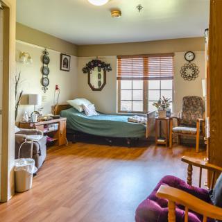 A cozy, well-decorated bedroom with a large window and wooden flooring.