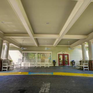 A covered entrance area of a building with columns and seating.