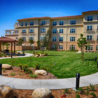 A residential building with a landscaped garden and lawn area.