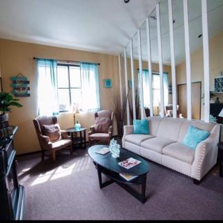 A cozy living room with a sofa, two chairs, and a coffee table, accented by natural light from a window with blue curtains.