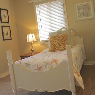 A cozy bedroom with a single bed, decorative pillow, and wall art.