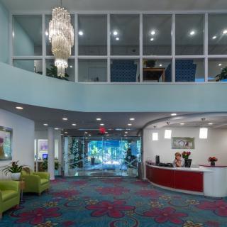 A modern lobby featuring a chandelier, reception desk, and seating area.