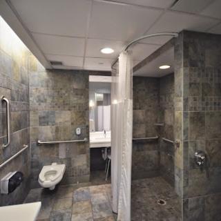 A modern accessible bathroom featuring a shower area with tiled walls.