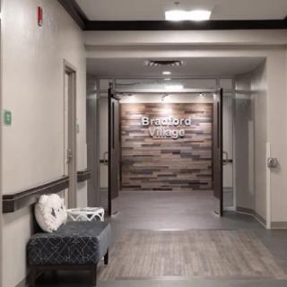 A clinic hallway with wood paneling and a bench.