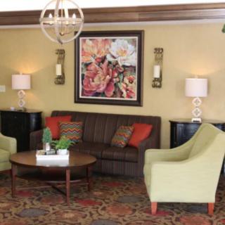 A cozy living room with a central coffee table, sofa, and two armchairs, complemented by artwork and soft lighting.