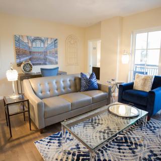 A stylish living room with a comfortable sofa, artwork on the wall, and a patterned rug.