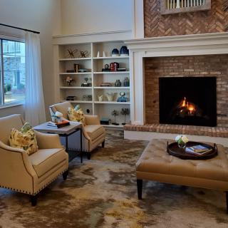 A cozy living room featuring a lit fireplace, comfortable armchairs, and a well-decorated bookshelf.