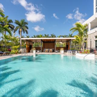 A luxurious outdoor swimming pool surrounded by palm trees at a tropical resort.