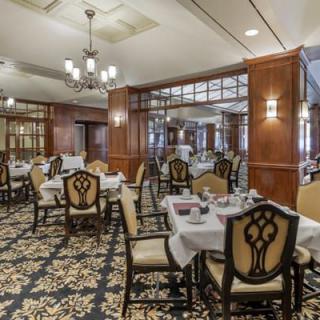 An elegant dining room with beautifully set tables and intricate chandeliers.