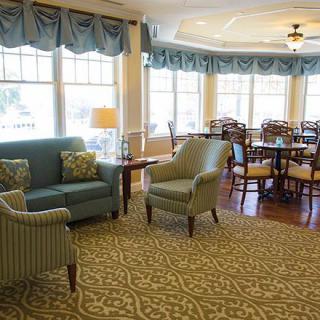 A cozy living room with a sofa, armchairs, and a dining area by large windows.