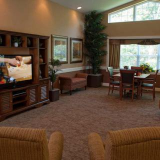 A cozy living room with a television, comfortable seating, and large windows offering plenty of natural light.