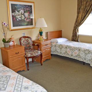 A cozy bedroom with twin beds, a nightstand, and decorative elements such as artwork and a lamp.