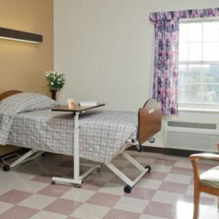 A hospital room with a single bed and a window providing natural light.