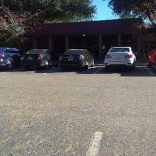 A view of a parking lot with several cars parked in front of a building on a sunny day.