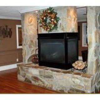 A stone fireplace in a cozy living room with a decorative wreath.