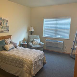 A cozy bedroom with a single bed, armchair, and soft lighting.