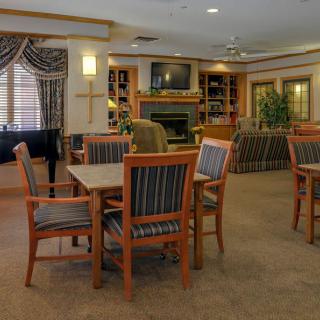 A cozy and elegantly furnished dining area with wooden chairs and tables, featuring a fireplace and television.