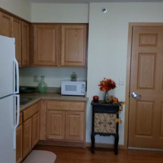 A cozy kitchen with wooden cabinets, a white refrigerator, and a microwave on the counter.