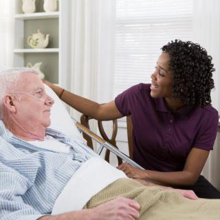 A caregiver attending to an elderly patient in a healthcare setting.