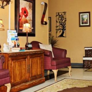 A cozy living room featuring red armchairs, a wooden cabinet, and decorative wall art.