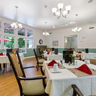An elegant dining room set up with tables and chairs, featuring chic chandeliers and tasteful place settings.