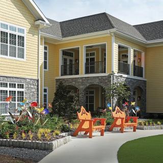 A charming yellow house with a garden and outdoor seating.