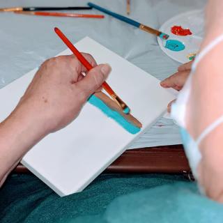 A person painting on a canvas using a brush.